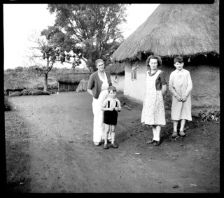 Belgisch-Kongo, Nioka: Kolonisten; Frau Noël mit ihren beiden Söhnen zusammen mit Ami Vivien vor ihrem Haus stehend