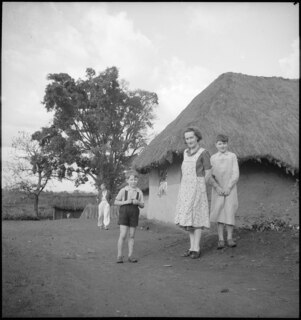 Belgisch-Kongo, Nioka: Kolonisten; Frau Noël mit ihren beiden Söhnen vor ihrem Haus stehend, Ami Vivien im Hintergrund
