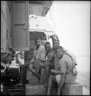 Belgisch-Kongo, Fluss Kongo: Soldaten; Vier farbige Soldaten sitzen barfuss zusammen auf dem Deck