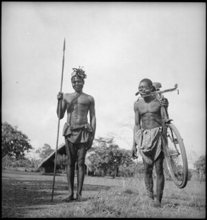 Belgisch-Kongo, Faradje: Menschen; Zwei jünge Männer des Stammes Azande, einer mit Lanze, der andere mit einem Velo auf der Schulter
