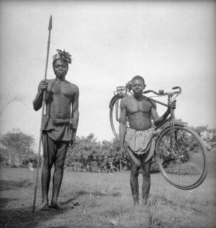 Belgisch-Kongo, Faradje: Menschen; Zwei jünge Männer des Stammes Azande, einer mit Lanze der andere mit einem Velo auf der Schulter