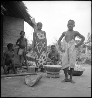 Belgisch-Kongo, Molanda (Malanda): Menschen; Mehrere Personen einer Familie des Stammes Gombé verarbeiten vor einer Holzhütte Maiskolben und posieren für die Kamera