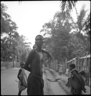 Belgisch-Kongo, Leopoldville (Kinshasa): Menschen; Strasse in Leopoldville mit zwei farbigen Männern im Vordergrund mit nackten Oberkörpern