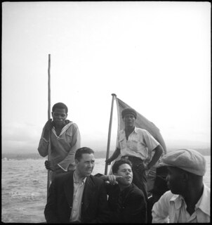Belgisch-Kongo, Fluss Kongo: Menschen; Zwei Portugiesen und mehrere farbige Männer auf einem Boot mit portugiesischer Flagge auf dem Kongo