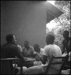 Belgisch-Kongo, Leopoldville (Kinshasa): Menschen; Mehrere farbige Männer sitzen im Kreis und spielen auf einem Tam-Tam (Trommel)