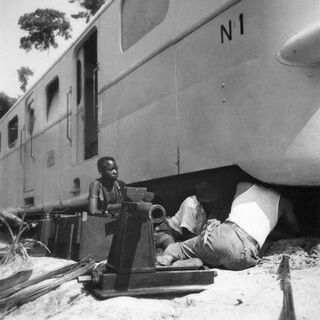 Belgisch-Kongo, Thysville (Mbanza Ngungu): Eisenbahn; Mehrere Arbeiter kauern neben oder unter dem entgleisten Zug mit Wagenheber daneben
