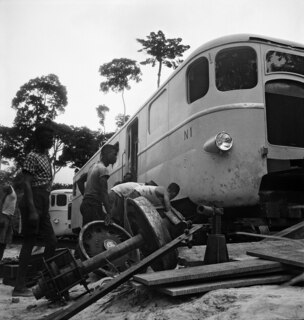 Belgisch-Kongo, Thysville (Mbanza Ngungu): Eisenbahn; Mehrere Arbeiter wechseln an einem Zug die Vorderachse und Räder aus