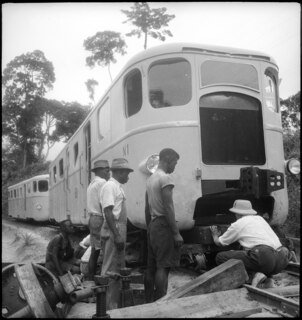 Belgisch-Kongo, Thysville (Mbanza Ngungu): Eisenbahn; Ein entgleister Zug ohne Vorderachse steht auf einer provisorischen Halterung auf den Geleisen umgeben von mehreren Arbeitern