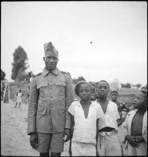 Belgisch-Kongo, Thysville (Mbanza Ngungu): Menschen; Uniformierter Soldat zusammen mit mehreren Kindern im Stadtteil "Belge" auf einem unasphaltierten Weg stehend