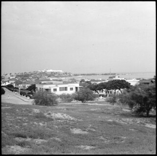 Portugiesisch-Westafrika, Luanda: Stadtansicht; Blick auf Hafenanlage mit einigen (Wohn) Gebäuden im Vordergrund