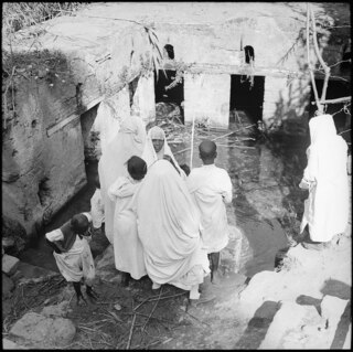 Französisch-Marokko, Rabat: Grabstätten Chellah mit Königsgrab Marabou; Mehrere teilweise verhüllte Frauen stehen vor einem katakombenartigen Wasserbecken (Brunnen)