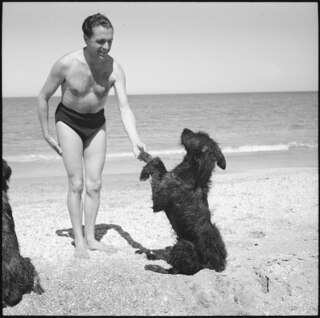 Spanisch-Marokko, Tétouan: Claude Clarac; Claude Clarac in Badehosen mit einem Hund (Ourmès oder Poulah?) spielend am Strand von Tétouan