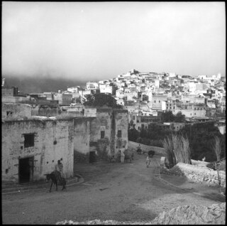 Französisch-Marokko, Moulay Idriss: Dorfansicht; Blick auf eine Strasse mit Dorfkern von Moulay Idriss im Hintergrund auf einem Hügel