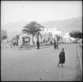 Spanisch-Marokko, Tétouan: Strassenszene; Kleiner Junge steht auf einer Strasse in Tétouan mit Wohnhäuser und Hügellandschaft im Hintergrund