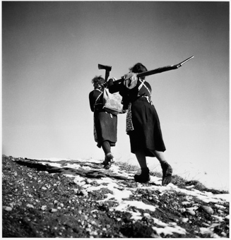 Zwei Frauen mit Werkzeug und Rucksack unterwegs auf einem Weg 