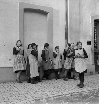 Mädchen vor dem Haus beim Brotessen