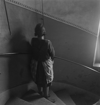 Mädchen auf Treppe stehend, über dem Treppengeländer zwei Fensteröffner