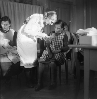 Lehrerin hilft einem Mädchen bei der Strickarbeit