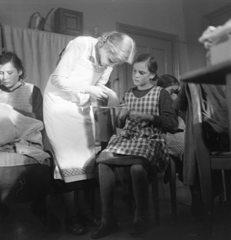 Lehrerin hilft einem Mädchen bei der Strickarbeit