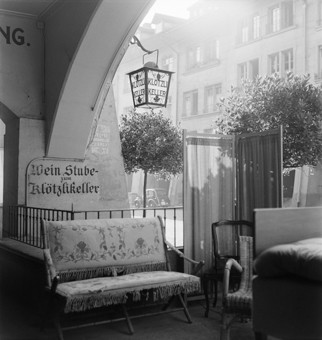 Weinstube zum Klötzlikeller Gerechtigkeitsgasse 62, Laubenbogen mit Sofa, Stühlen, Paravent und ein Bäumchen. Wirtshausschild «Klötzlikeller» (Laterne)