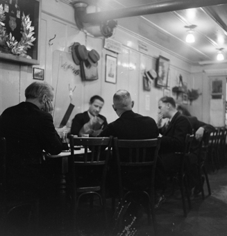 Männerrunde am Jassen in Wirtshaus der Altstadt. An der Wand diverse Hüte, Werbeplakat St. Moritz von 1934, in einem Holzkasten Kranz und Medaillen eines Sportvereins