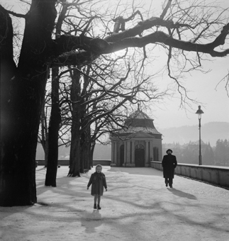 Kind in Winterkleidern auf der verschneiten Münsterplattform. Bäume, Pavillon, Kandelaber