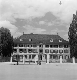 Ehemaliges Waisenhaus, Sitz von Kantonspolizei und Stadtpolizei. Fahrräder vor dem Gebäude. Zwei Fussgänger mit Mappe und Tasche, ein Fussgänger im Laufschritt