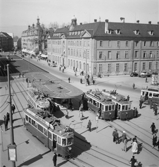 Tram-Häuschen und Kiosk, Tram Nr. 4 von 1935, Trams Nr. 5 und 6 von 1910. Vorne links im Bild Pfeiler mit Fahrplan «Stadt-Omnibus». Oben der Burgerspittel und das Franke-Haus, daneben das begrünte Tram-Trassée