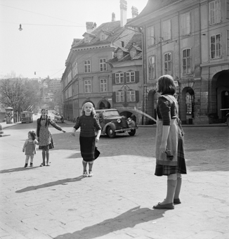 Vier Kinder mit Springseil. Im Hintergrund Nydegggasse und Nydeggbrücke, links eine Plakatsäule und Trolleybus S aus der Schosshalde herkommend. In der Bildmitte Haus Junkerngasse 1 mit Wappen und Aufschrift «Möbelfabrik Metti&Cie»