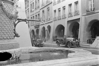 Wasserhahn von Mosesbrunnen mit Vogel. Im Hintergrund die Kesslergasse mit Markttischen und parkiertem Auto