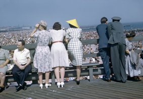 Menschen auf dem Pier sitzend und stehend, daneben zahlreiche Menschen am Strand und im Wasser 