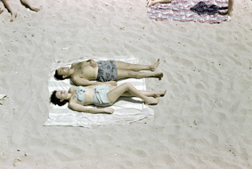 Sich sonnendes Paar in Badeanzug auf einer Decke liegend