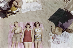 Zwei Frauen und ein Junge am Sandstrand auf einer Decke liegend, sich sonnend