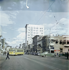 Gelbe Strassenbahn, Autos und Passanten, Häuser mit Restaurant-Schildern, Hotel Anchor und Hotel Troy