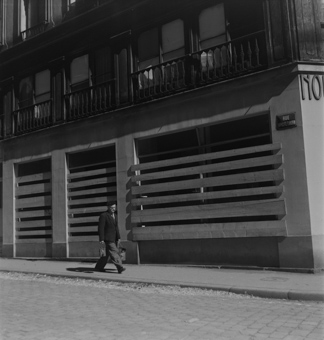 Passant auf Trottoir vor einem Haus mit verbretterten Fenstern