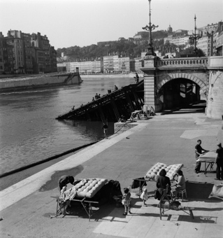 Handwerker-Familie bei der Arbeit mit Matratzen, Uferpromenade der Saône, Fischer, im Hintergrund Soldaten auf der zerstörten Pont de la Feuillée