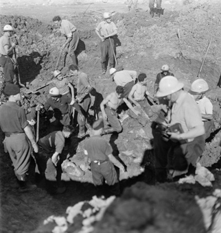 Rotkreuzfreiwillige und Soldaten bei Ausgrabungsarbeiten