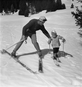 Kind und Skilehrer Hand in Hand auf der Piste