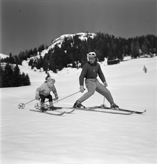 Kind und Skilehrer nebeneinander in Fahrt