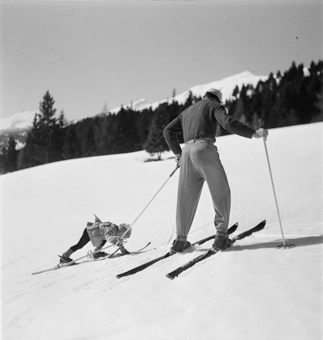 Skilehrer hilft Kind beim Aufstehen
