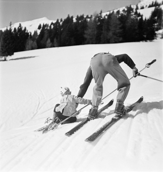 Skilehrer hilft Kind beim Aufstehen
