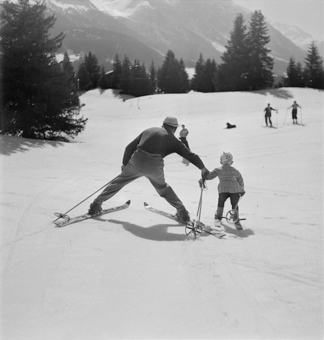 Kind und Skilehrer Hand in Hand auf der Piste