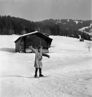 Kind auf kurzen Skis (Fassdauben) fährt einen Hang runter