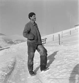 Bauer in Arbeitskleidung auf einem verschneitem Hang