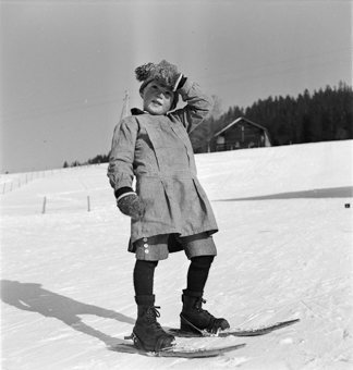 Kind in Winterkleidung auf kurzen Skis (Fassdauben)