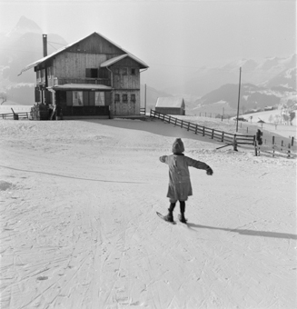 Kind fährt auf kurzen Skis (Fassdauben) den Hang runter