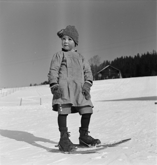 Kind in Winterkleidung auf kurzen Skis (Fassdauben)
