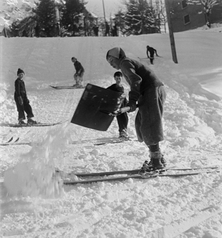 Kinder auf Skis bauen eine Sprungschanze