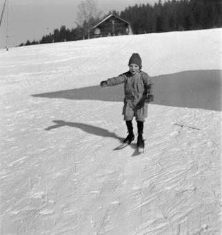 Kind fährt auf kurzen Skis (Fassdauben) einen Hang runter