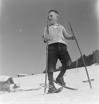 Knabe mit Fassdauben (kurzen Skis) und Skistöcken